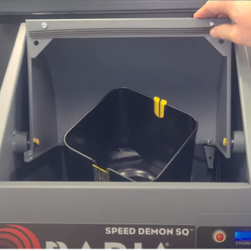 Photo of a Radia Speed Demon™ SQ mixer with the front lid open, showing a square paint can seated inside the mixing cradle while a hand rests on the top frame.